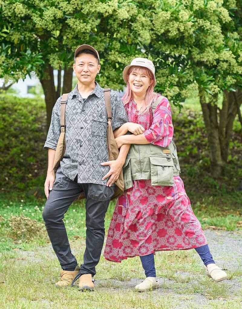 腕を組んで笑顔でポーズをとる、さいとう夫婦