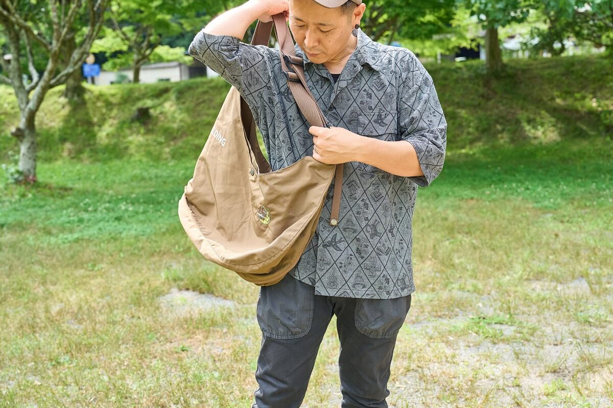 着ていたベストをショルダーバッグに変えているところ