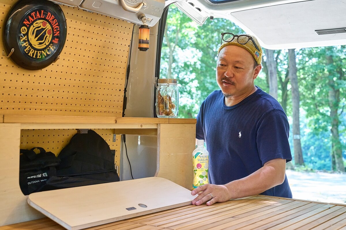 車中泊カスタムしたデリカバンのサイドテーブル兼コンソールについて説明している宮﨑秀仁さん