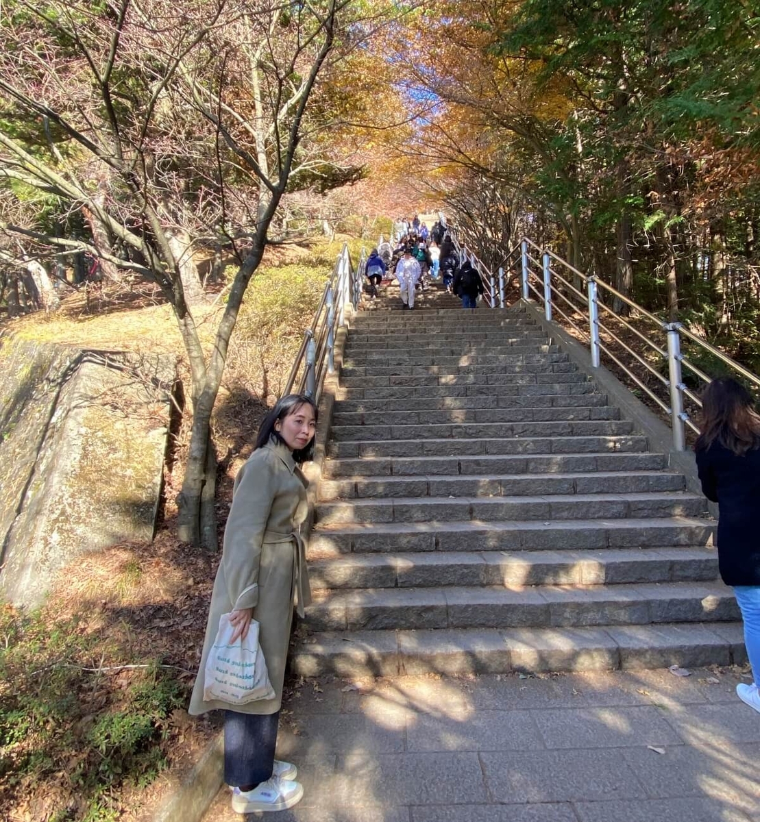  新倉富士浅間神社の「咲くや姫階段」の前に立つ辛酸なめ子さん