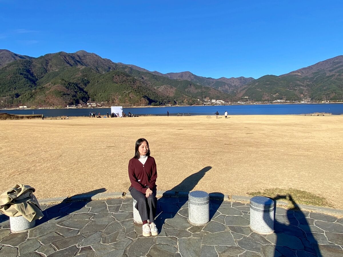 河口湖に面した八木崎公園のベンチに座る辛酸なめ子さん