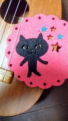 ウクレレに黒猫のコースターを挟んだ写真