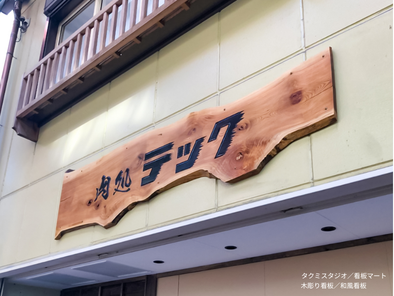 和食店の店名を彫り込んだ木彫り看板。天然木の風合いが空間に溶け込む。