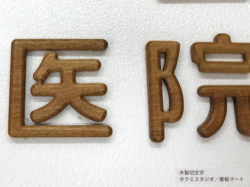 店舗外壁に設置された立体的な木製切文字。自然素材の温かみを活かしたデザイン。