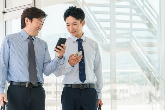 スマホを見ながら街を歩く男性ビジネスマン