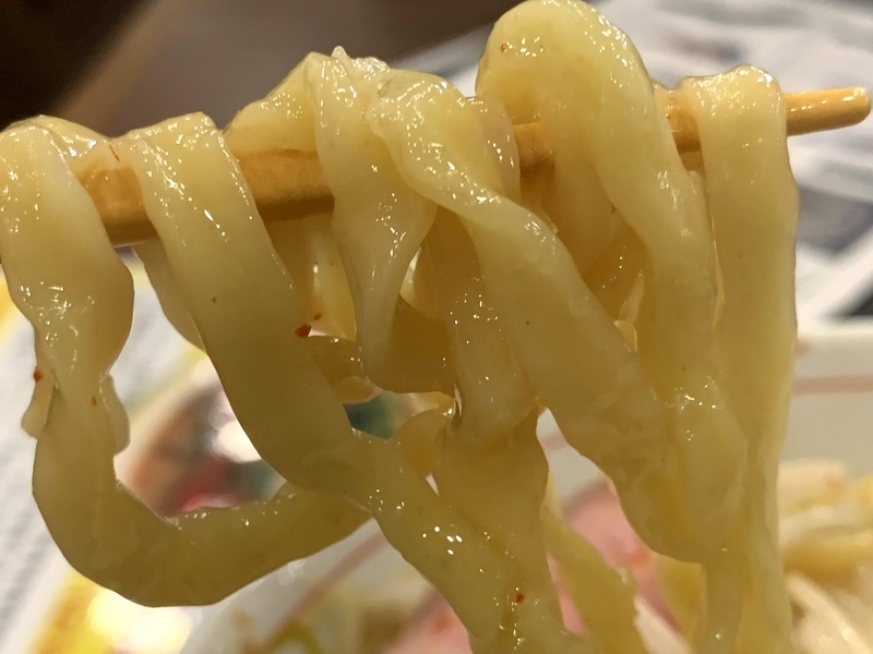 ラブメンのちぢれ平麺を箸で持ち上げた写真