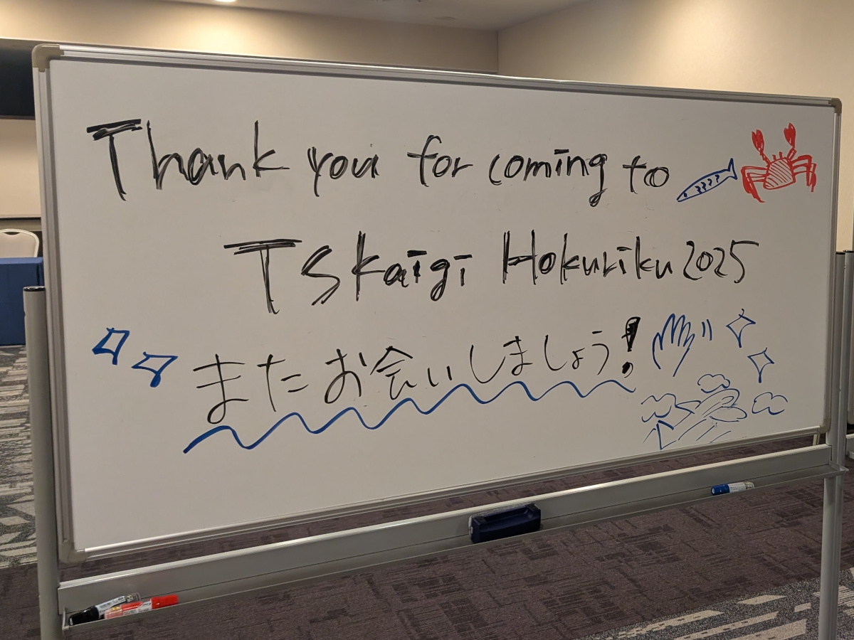ホワイトボードに「Thank you for coming to TSKaigi Hokuriku 2025 またお会いしましょう！」と手書きでメッセージが書かれ、周りにカニや魚、波や手を振るイラストが描かれている。