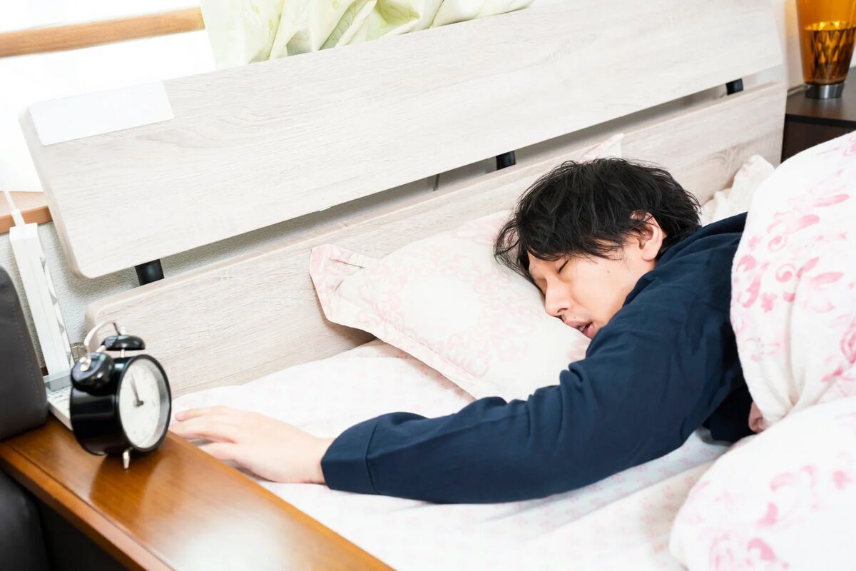 目覚まし時計をセットするものの、起きることができない男性