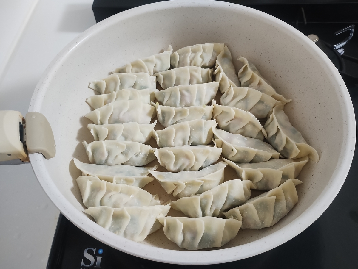 フライパンに並べた焼く前の手作り餃子の写真