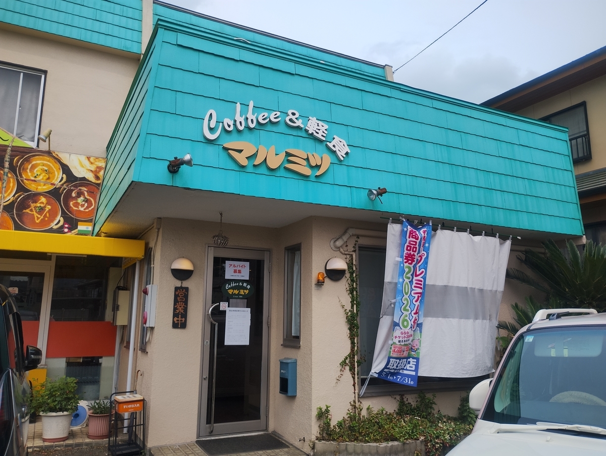 各務原市にある喫茶店『マルミツ』の外観。ターコイズブルーの屋根と看板が目を引く入口には『Coffee&軽食 マルミツ』の文字があり、営業中の札が掛かっている。