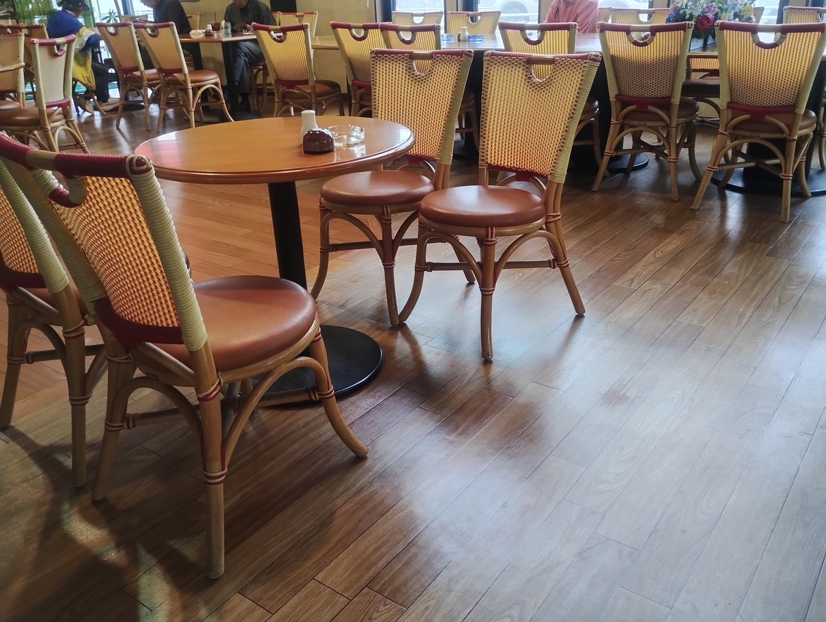 カフェ店内の様子。木の床に丸テーブルと籐風の椅子が並び、明るい雰囲気の客席エリア