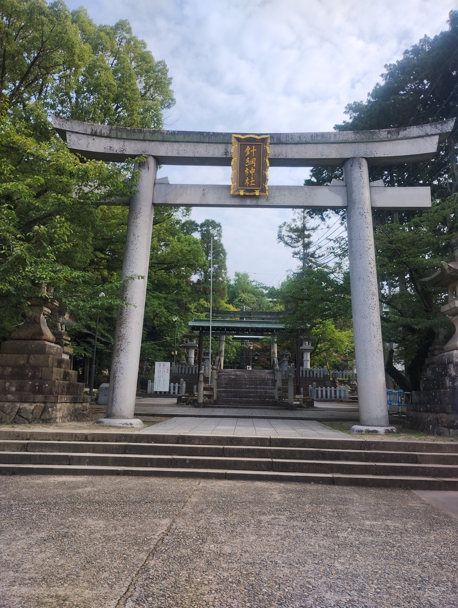 針綱神社の鳥居。白い石造りの大きな鳥居の奥に参道が続いている。