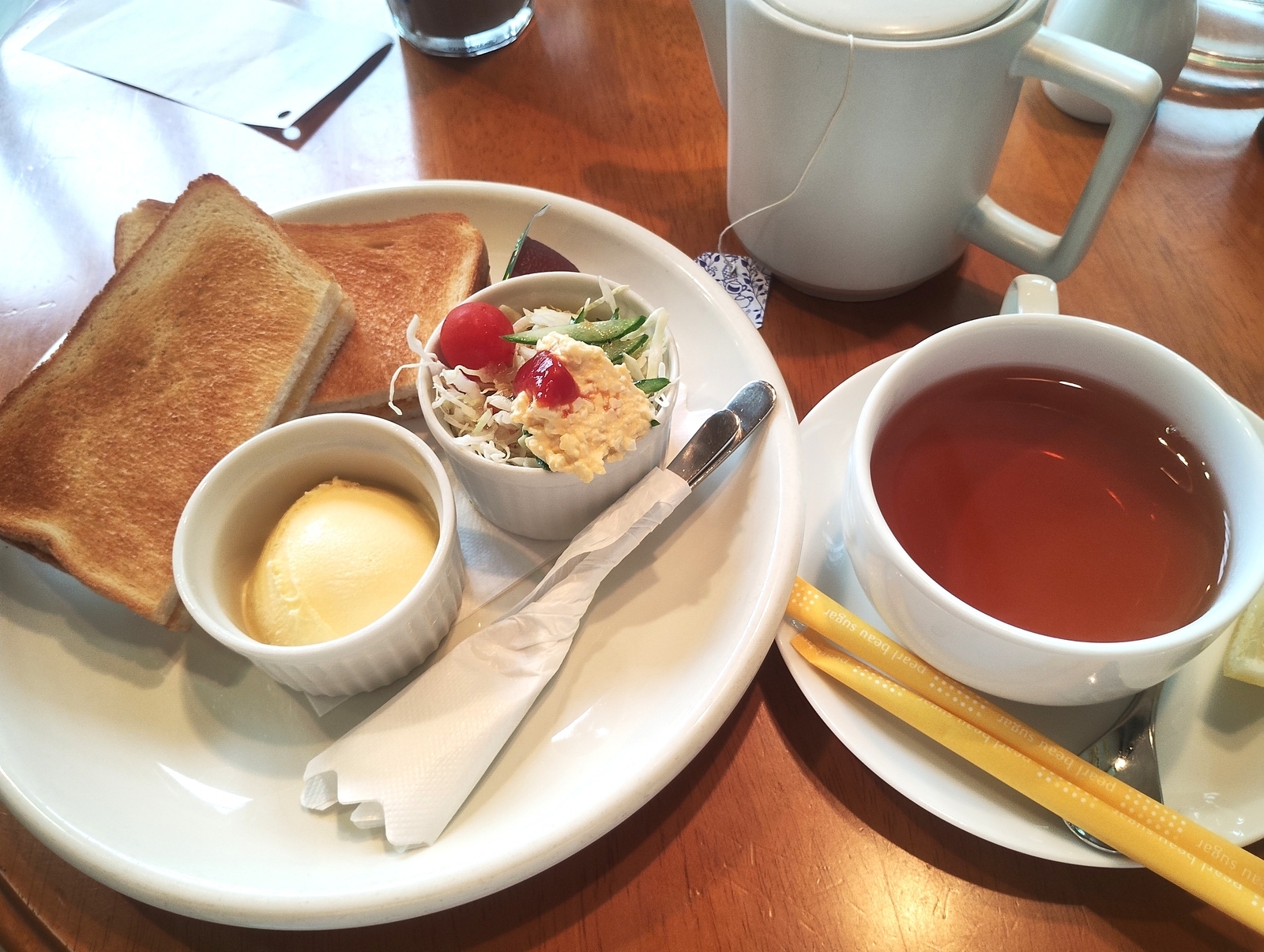 「トースト、サラダ、バター、紅茶が並ぶ喫茶店のモーニングセット