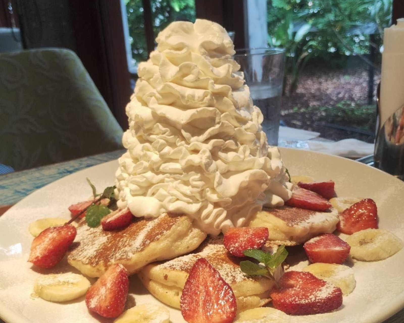 いちごとバナナを添えたパンケーキに、山のように盛られたホイップクリームがのったスイーツプレート