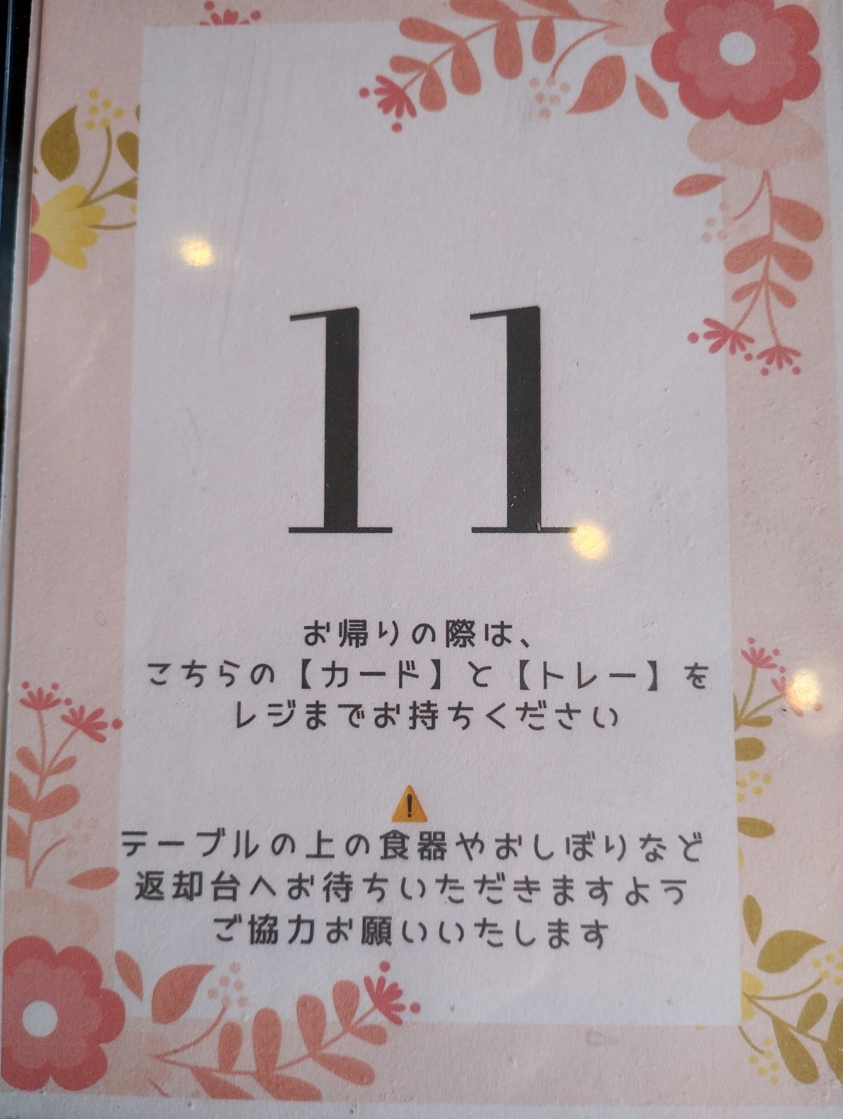 ユコーネの席番号札「11」。花柄のデザインで、セルフスタイルの案内文が添えられている。