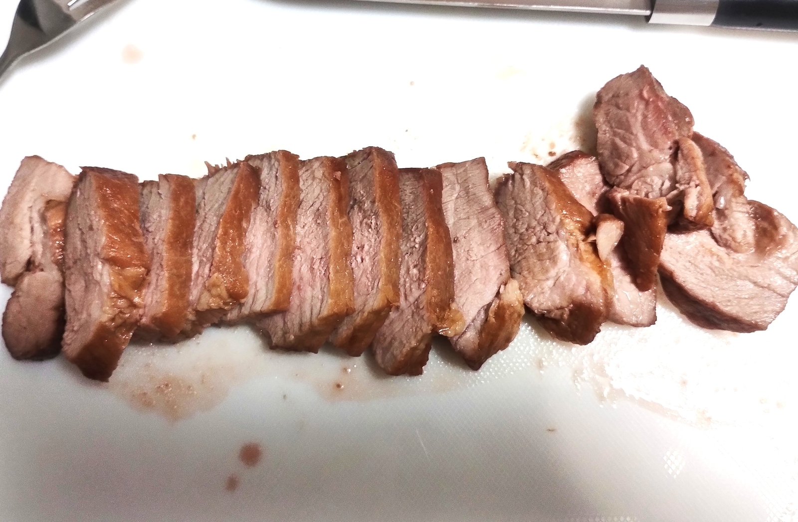 まな板の上に並べた焼豚。均等に切り分けられた断面から、しっとりとした肉の質感が見える。