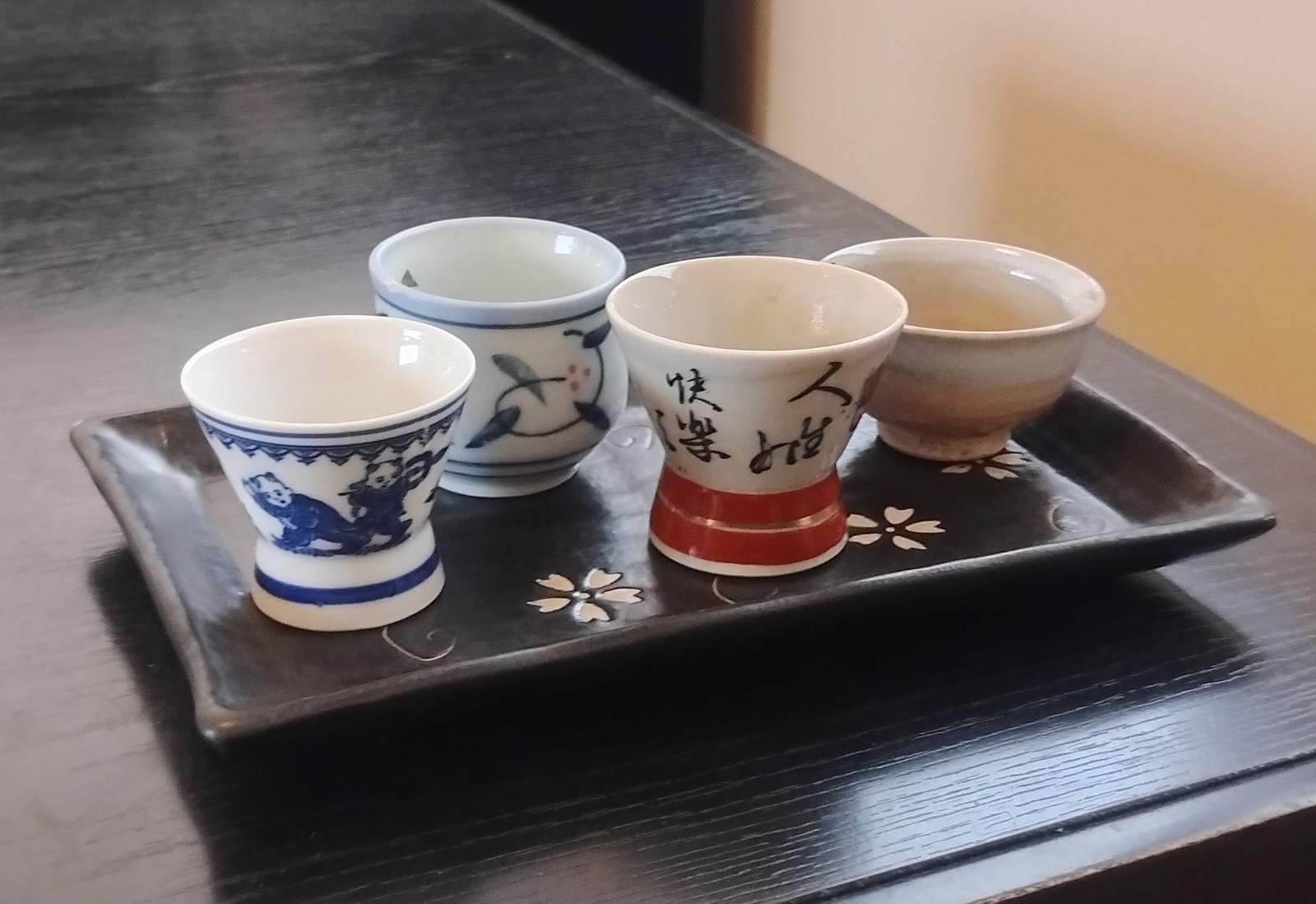 茶色のお盆におちょこが4つ並んでいる