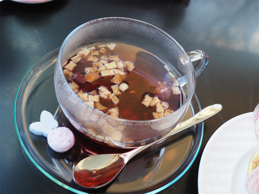 フルーツティーの写真。果実が浮かぶお茶の横にはかわいらしい砂糖菓子が添えられている。