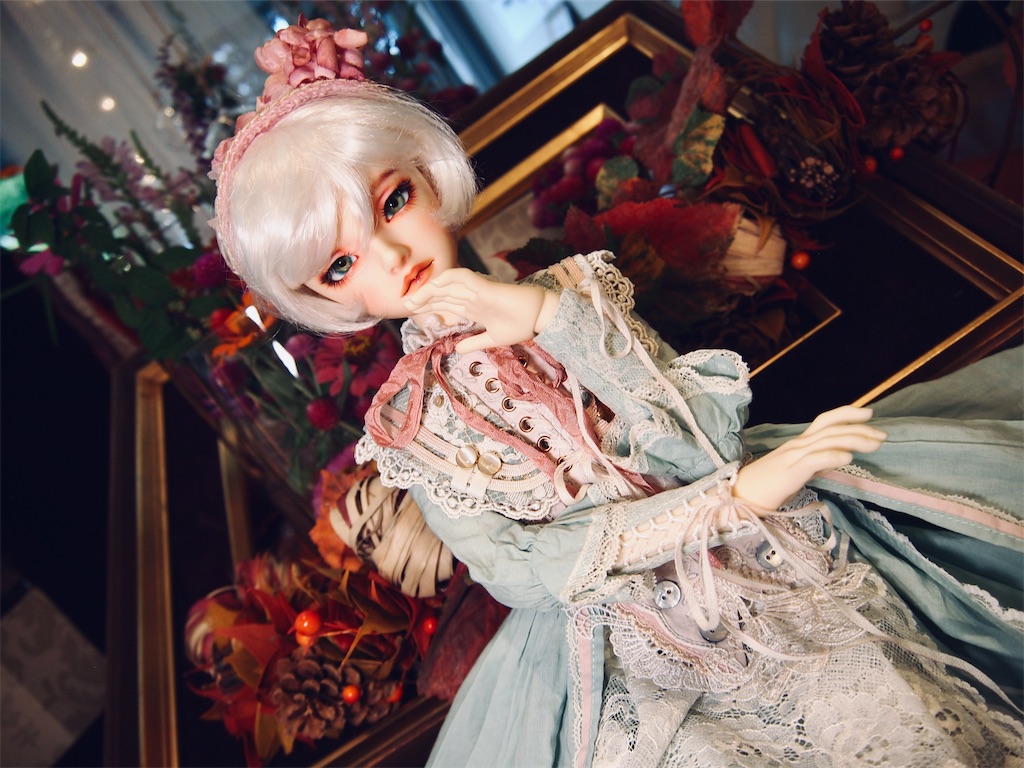 コスモスなどの秋の花を背景に、ピンクの紫陽花のヘッドドレスとミントグリーンのドレスを着ているつかさくんの写真