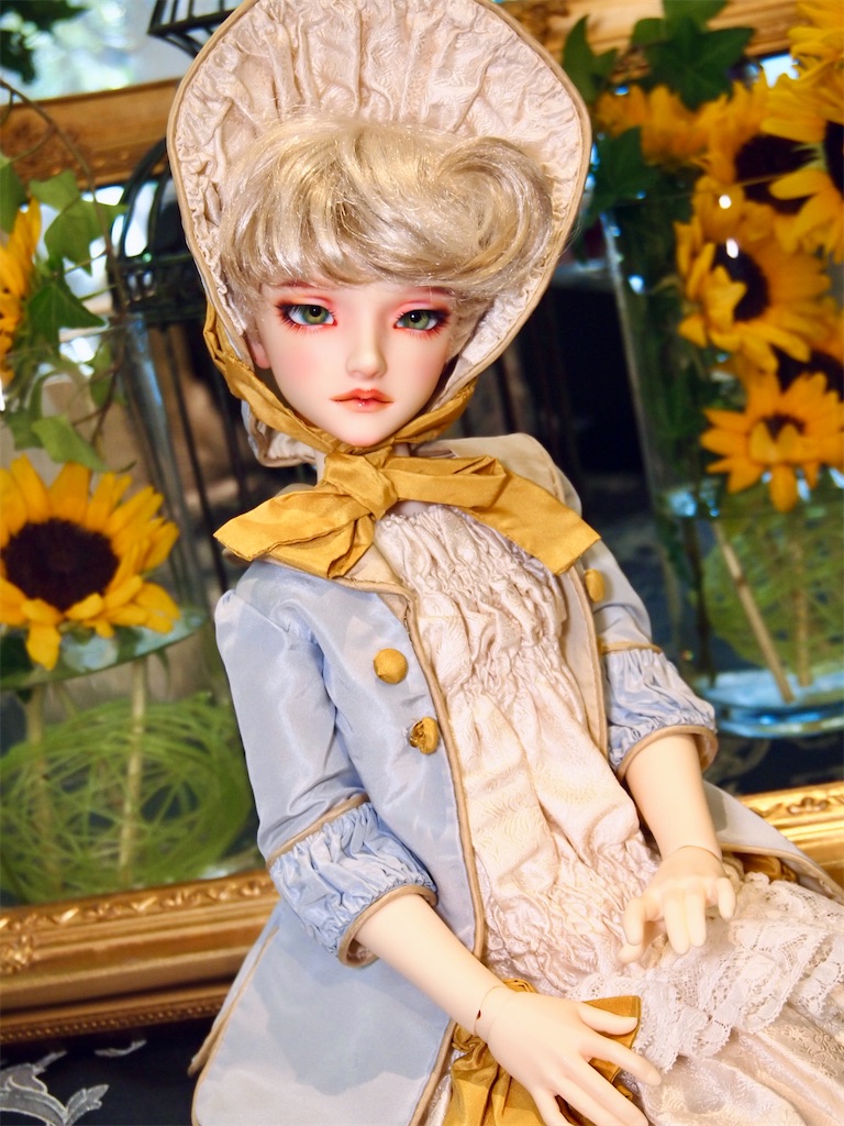 向日葵で飾られたブビンガ大テーブルの上に座るつかさくんの写真