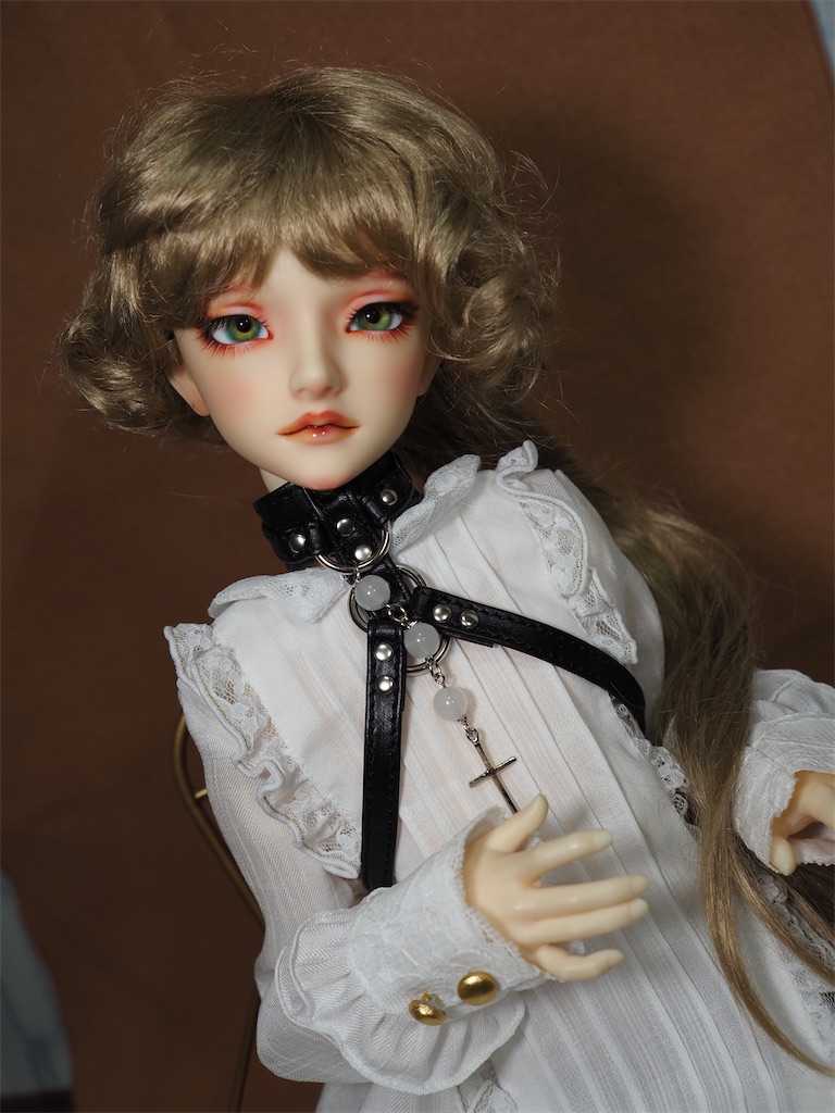 黒い革のボディチョーカーを白いブラウスの上から着けたつかさくんの写真。