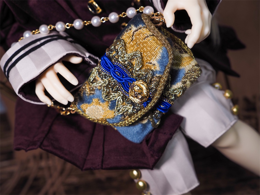 青い上質な布地で作られたドールサイズの小さな鞄の写真。