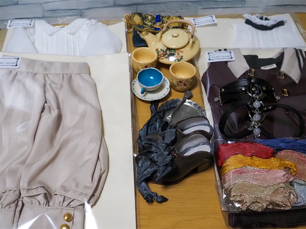 購入品の写真。お洋服4着、茶器、ティーカップとソーサー、靴、染リボン、ボディチョーカーが写っている。
