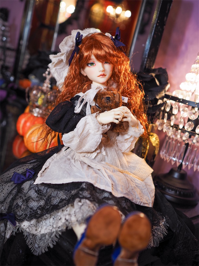 黒いドレスを着た赤毛のつかさくんがテディベアを抱いて座っている写真。