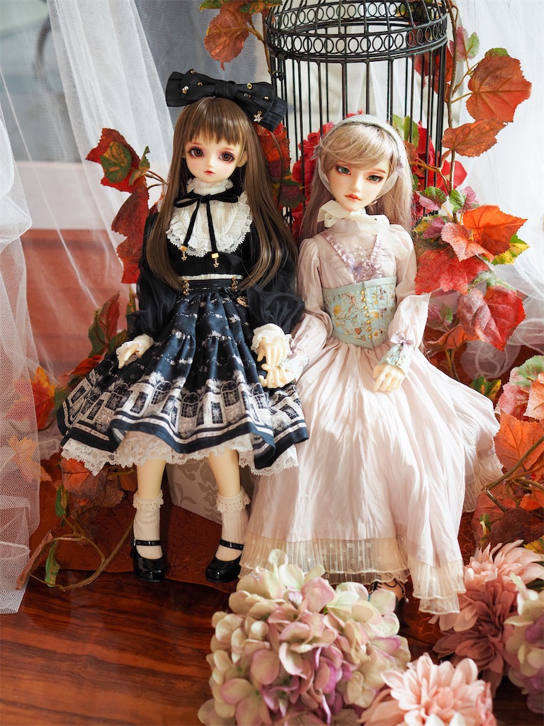 黒いドレスを着た有紗ちゃんとピンクのドレスを着たつかさくんが並んで手を繋いで座っている写真。