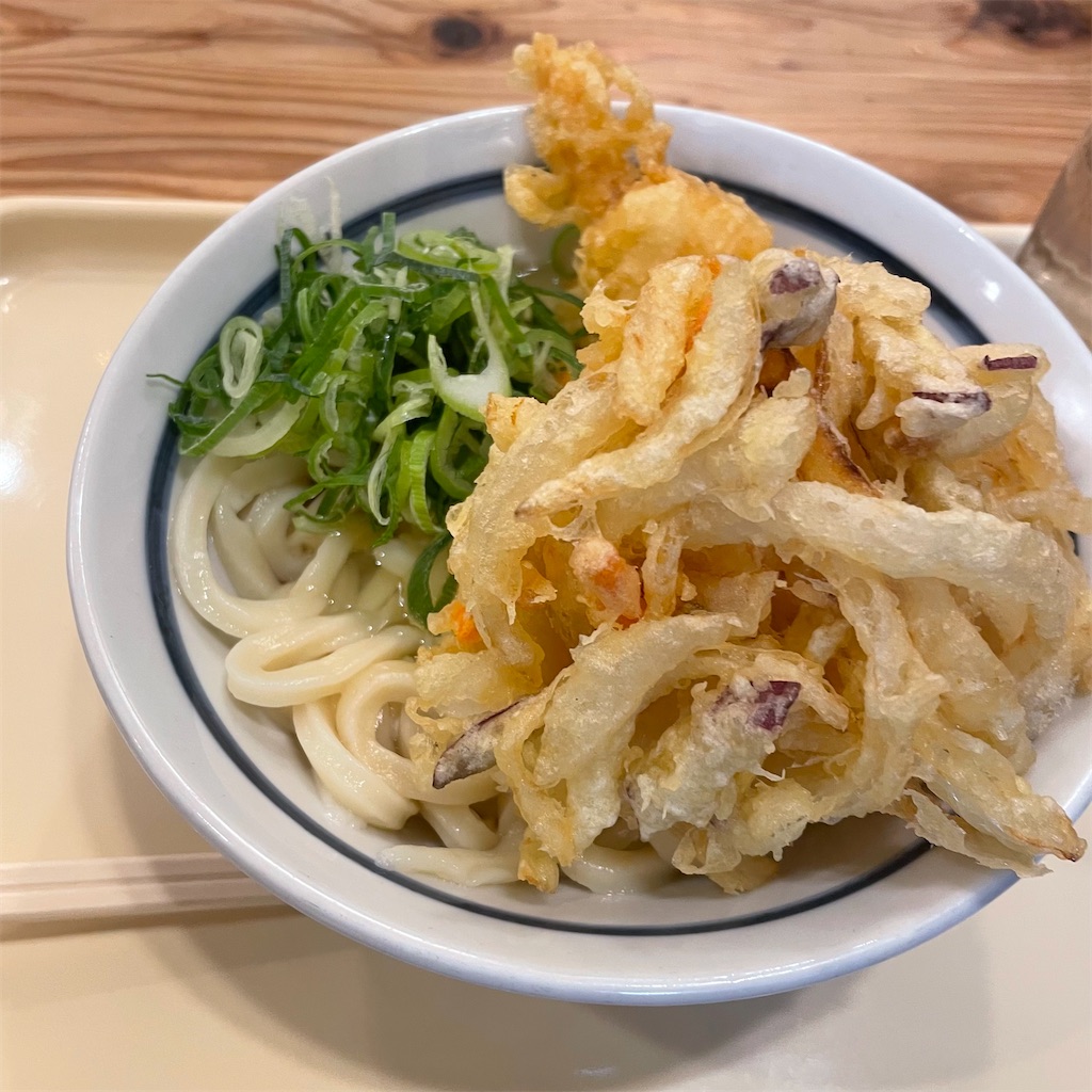かしわ天や野菜のかき揚げが載った釜玉うどんの写真。