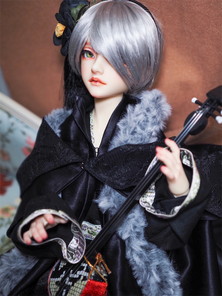 黒い和風のドレスを着て、黒い椿の髪飾りを着けて三味線を持っているつかさくんの写真。