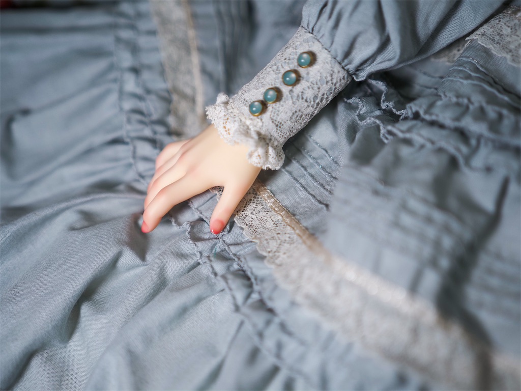 くすみグリーンのドレスを着たつかさくんの右手をアップにした写真。右手にはリアルなピンク色のメイクが施されている。