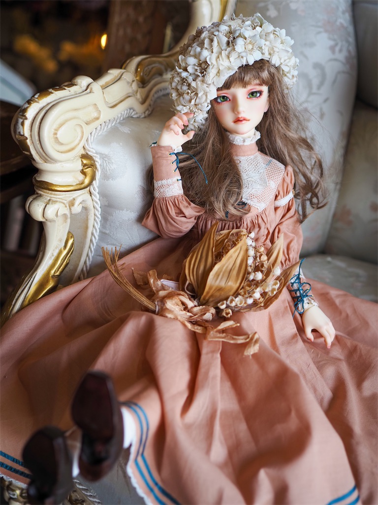 テラコッタオレンジのドレスを着たつかさくんの写真。右手でエクリュのベレー帽を押さえている。