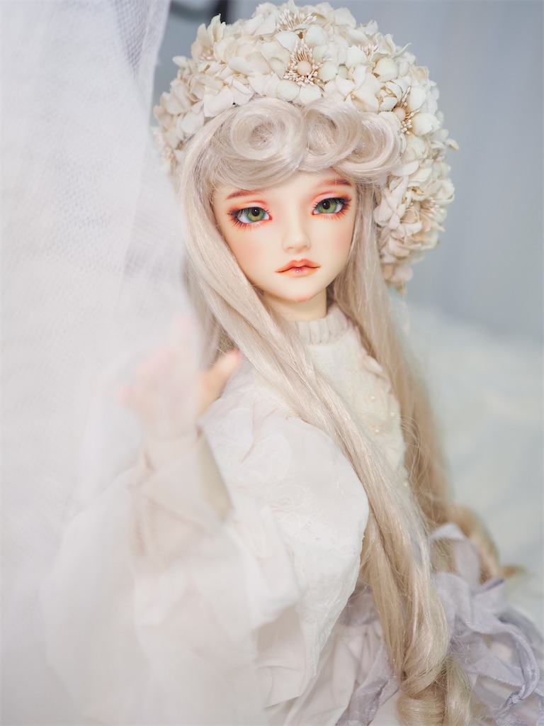 アイボリーの布花のベレー帽を被り、白いドレスを着たつかさくんの写真。髪はブロンドのカールヘア。