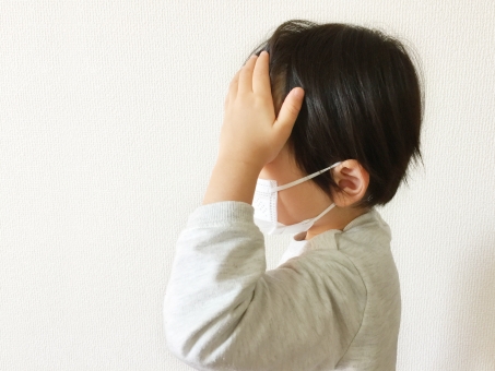 おでこに手を当てるマスクをした子ども おでこに手を当てるマスクをした子ども