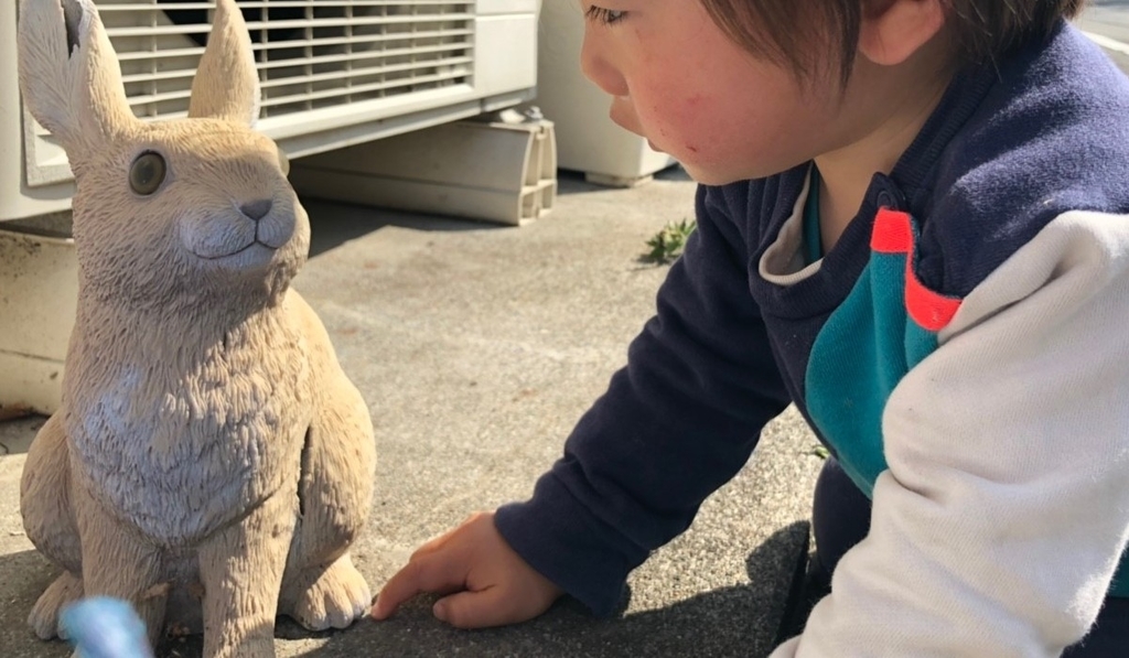 うさぎのぬいぐるみにに興味を持つ子どものの写真