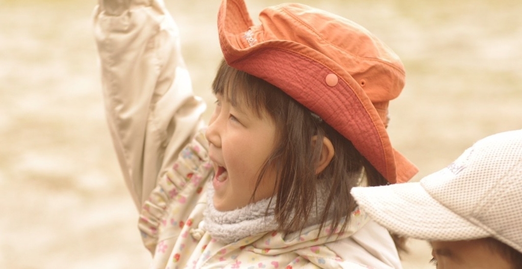 自然の中で元気に手を上げる女の子の写真