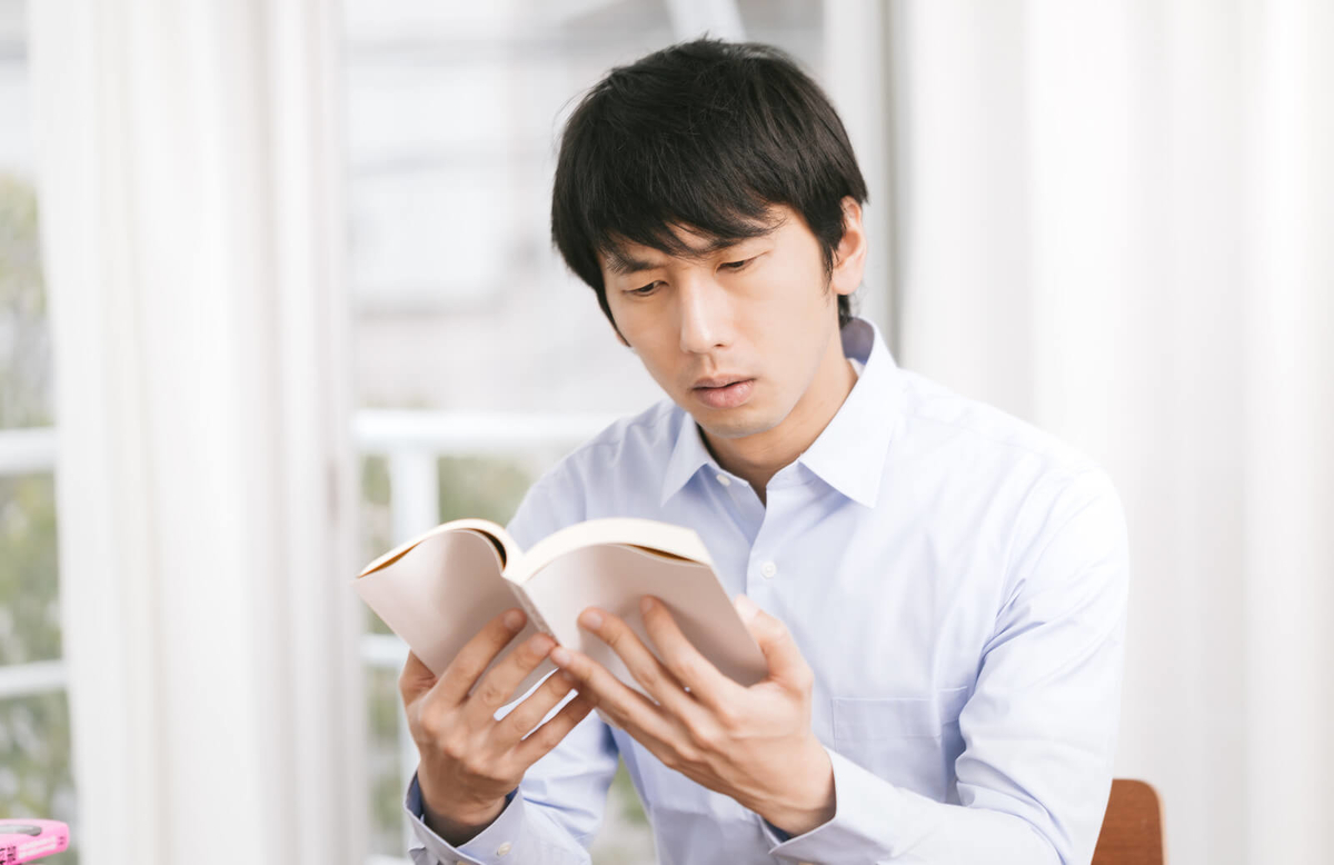 難しい顔をして本を読む男性