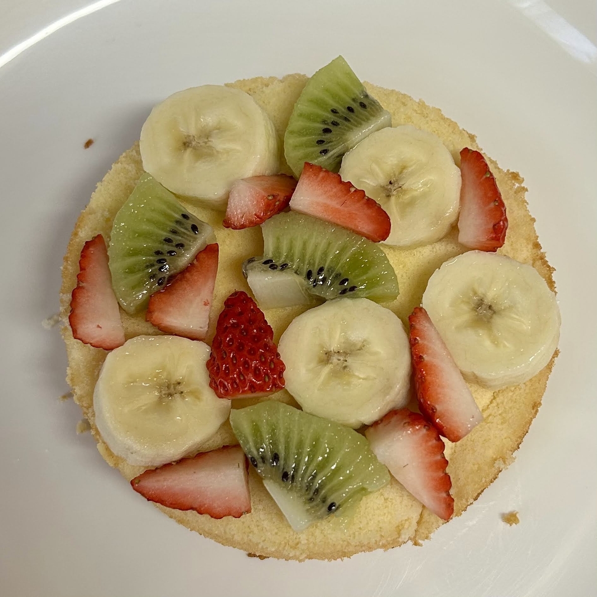 スポンジケーキの上にフルーツを並べたところ