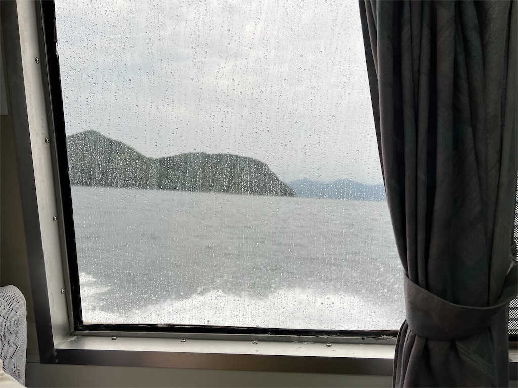 雨がついた窓から海が見える