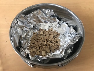 クッカーにアルミホルを敷き、スモークチップを乗せます。