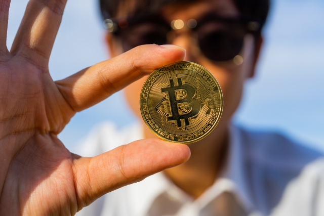 ビットコインを指でつまんでいる男性