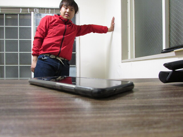 スマホを遠くから眺める男性