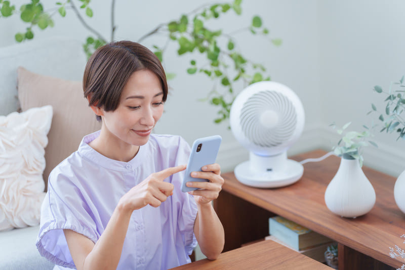 涼しい部屋でスマホを使用する女性