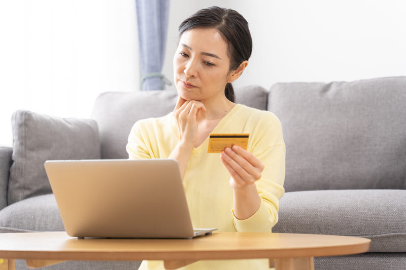 キャッシュカードを手に持ち悩む女性