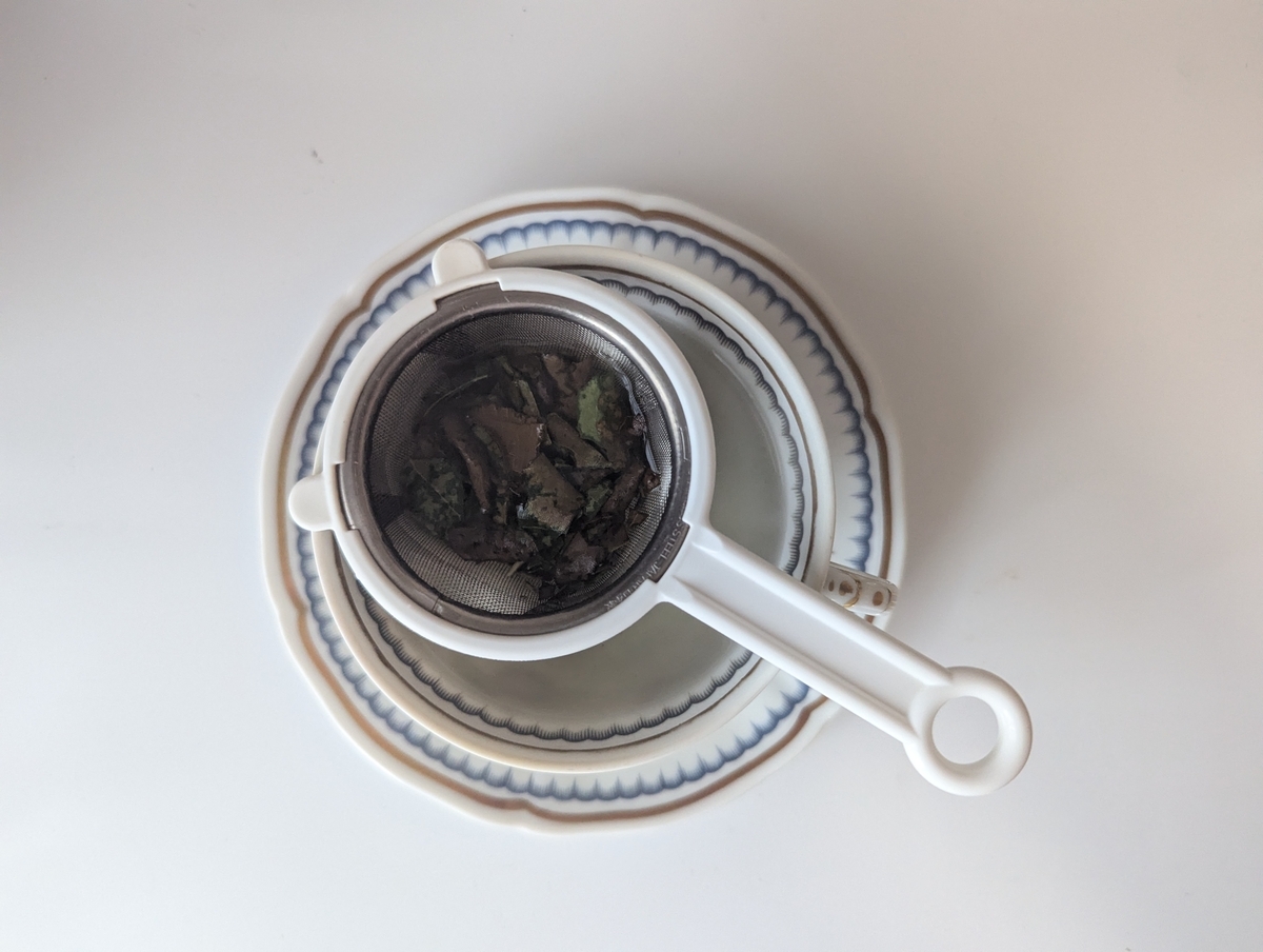 茶こしに砕いたびわの葉を入れる