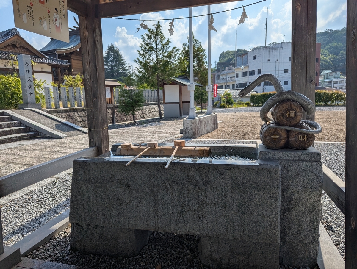 手水舎の横には、福・幸・財を背負った蛇の像。白蛇は弁財天の使いとしても知られ、金運アップの象徴。