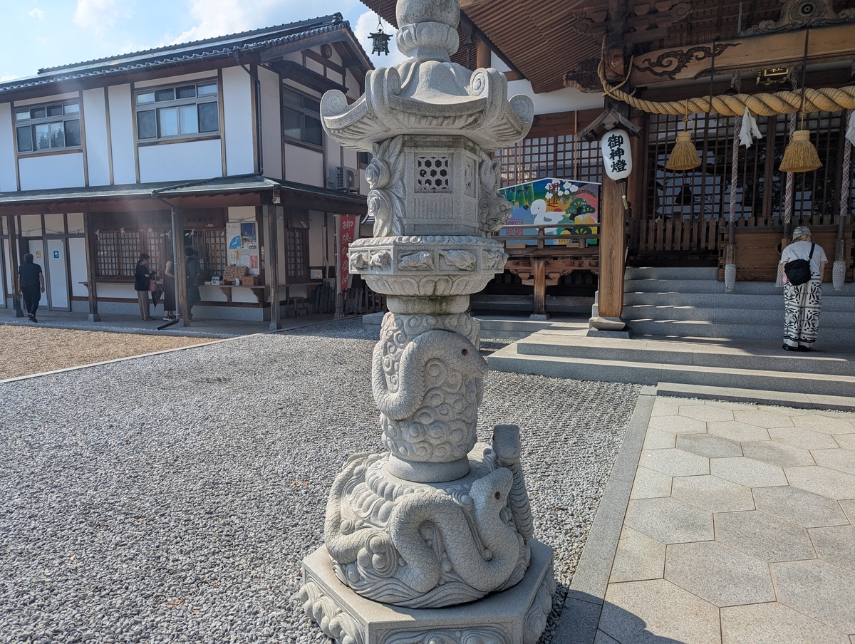 境内の灯籠にも蛇の彫刻が。随所に“白蛇づくし”の神社、金運スポットとして人気なのも納得。