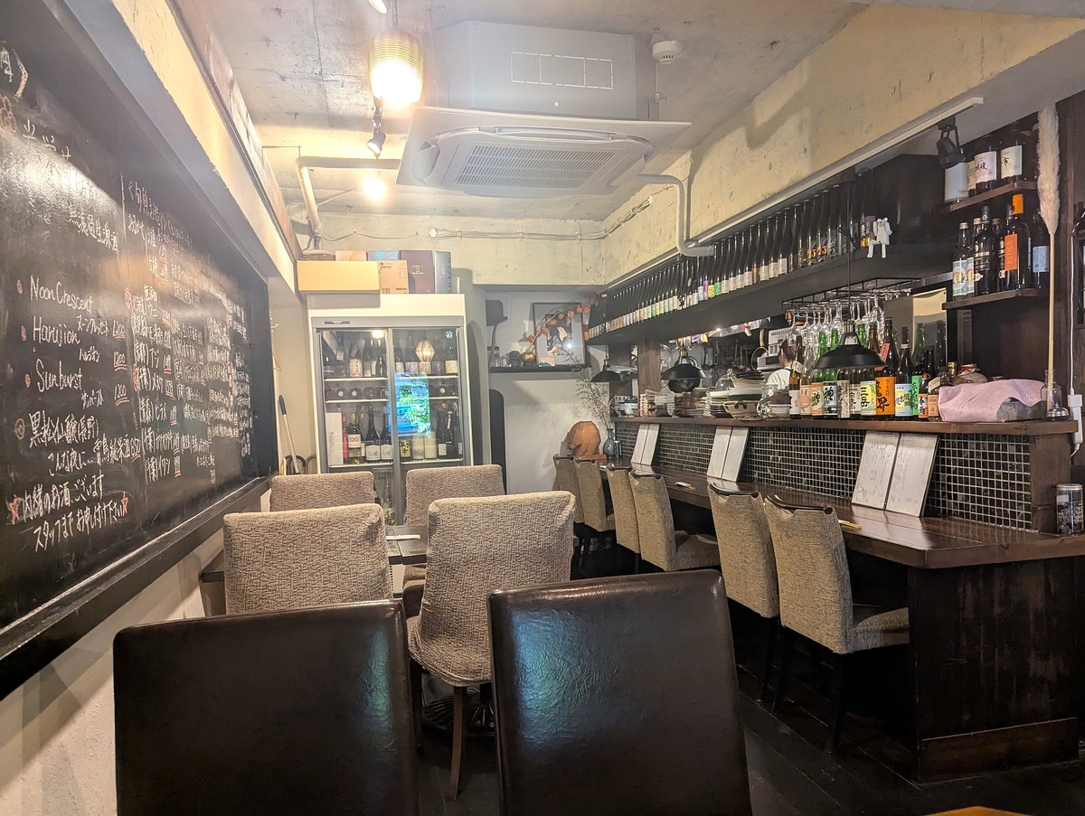 カウンター席とテーブル席が並ぶ落ち着いた店内。日本酒のボトルがずらりと並び、お酒好きにはたまらない雰囲気。