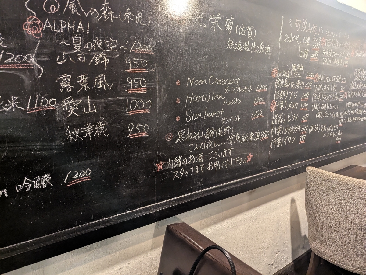 カウンター席とテーブル席が並ぶ落ち着いた店内。日本酒のボトルがずらりと並び、お酒好きにはたまらない雰囲気。